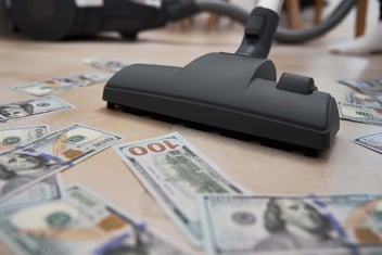 lavagem de dinheiro representada por um aspirador de pó aspirando notas de dolar