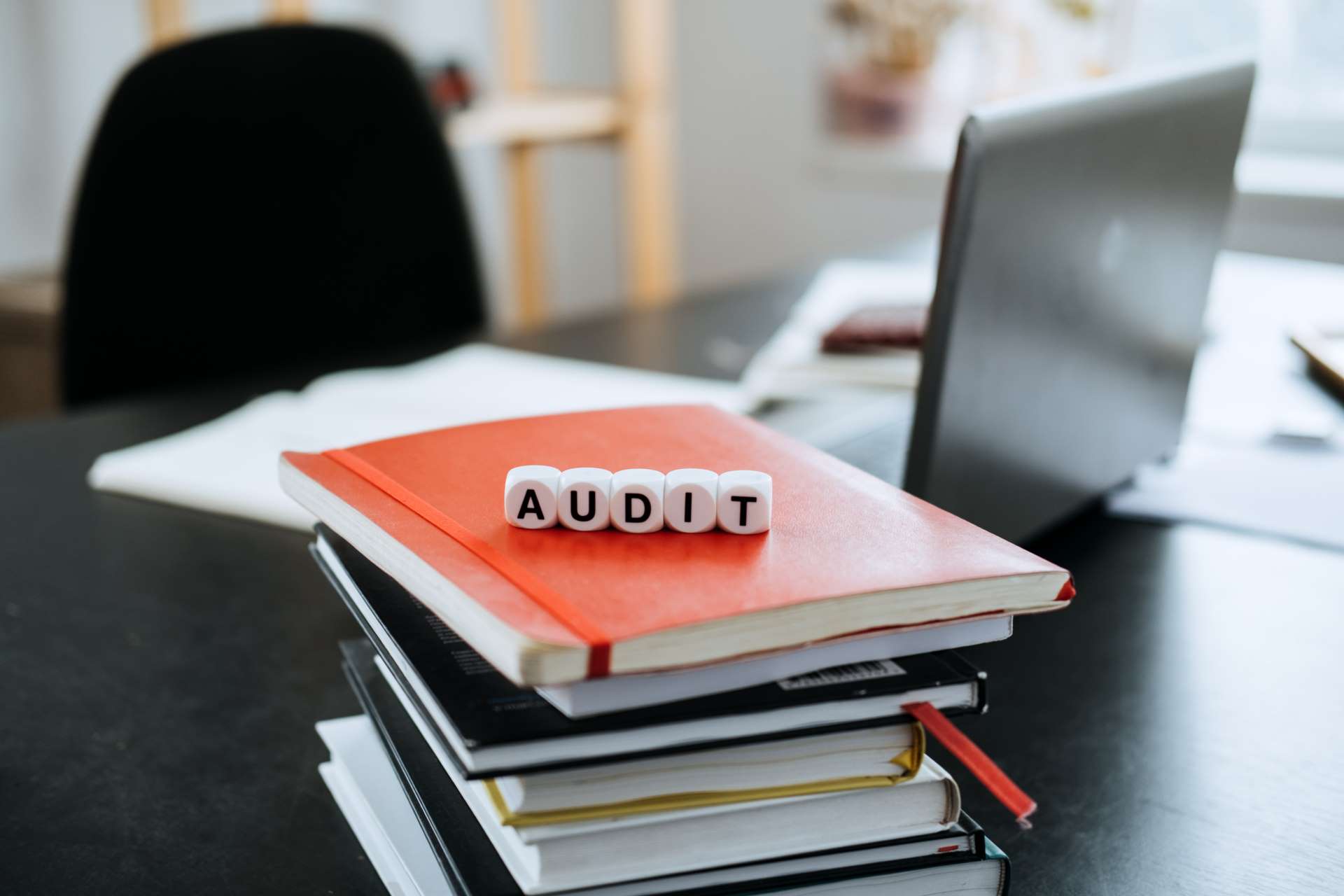 cubos com letras formando a palavra auditoria em cima de documentos para representar a importância da auditoria interna
