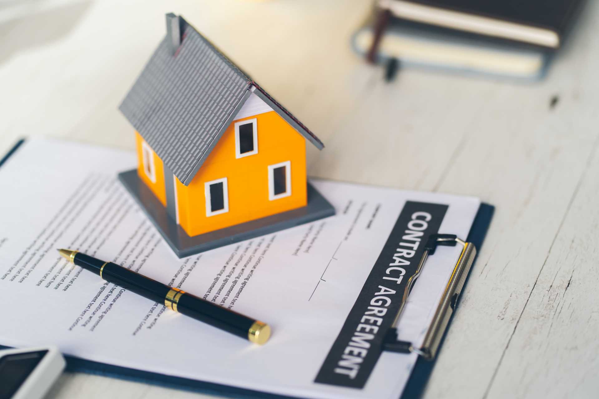 maquete de casa em cima dos documentos de due diligence imobiliária